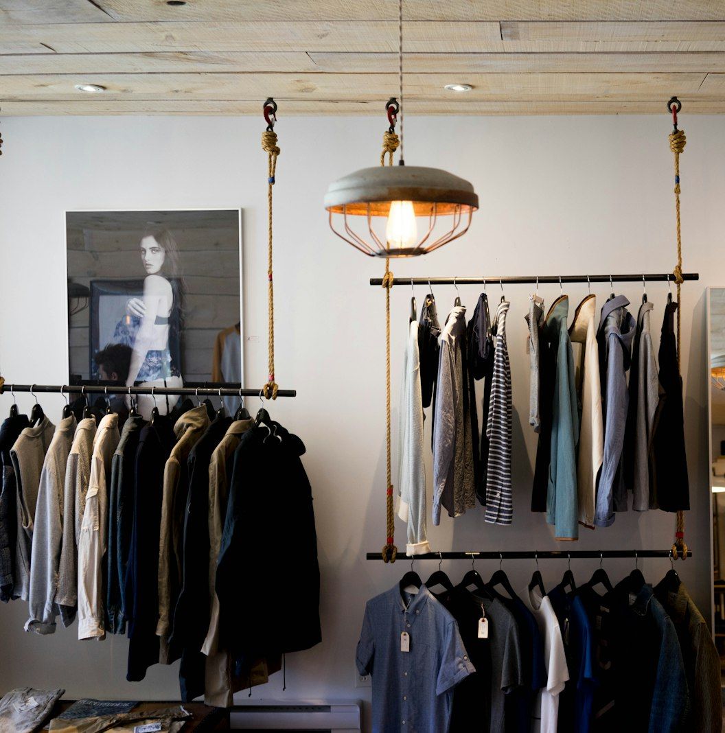 A storefront interior with clothing rails and pendant lamps